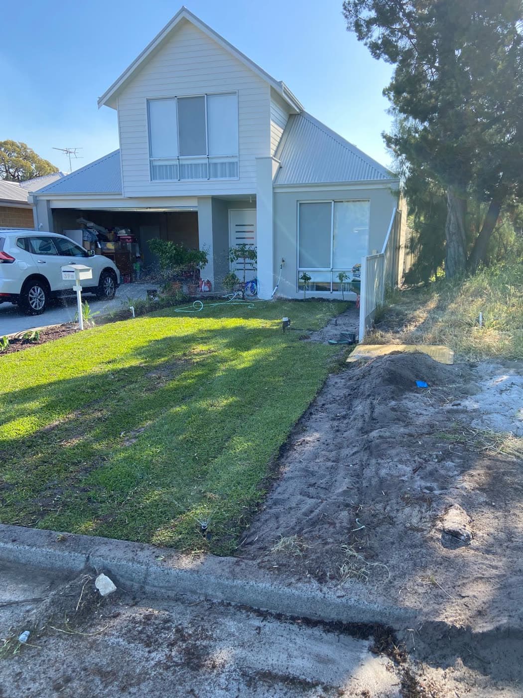 Finished front lawn — fresh turf with the reticulation running.